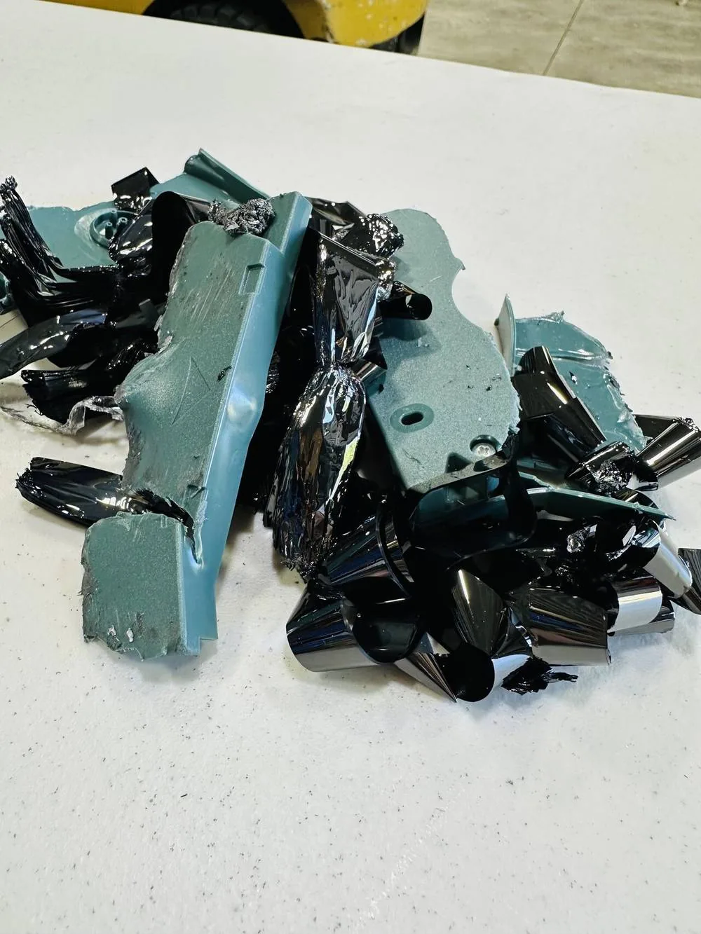 A destroyed LTO tape cartridge with the tape spooled out and the plastic shell in pieces